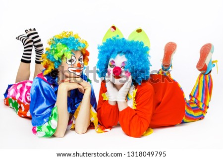 Two clown girls lie on his stomach and lean his head on his hands.