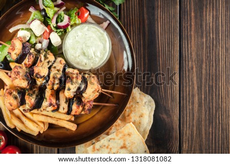 Chicken Souvlaki with french fries and tzatziki sauce. Greek dish on a plate. Top view