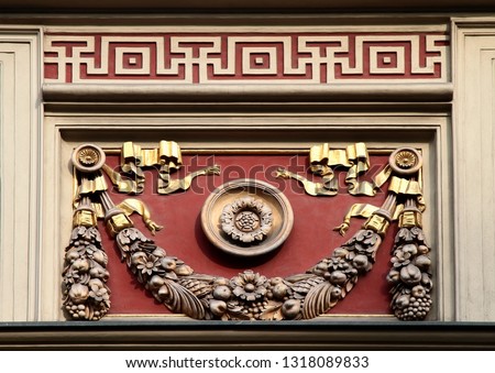 Architectural decorative element of building. Eagle standing on a garland of fruits and flowers carved of stone on red background. Salt Market Square. Wroclaw. Poland.