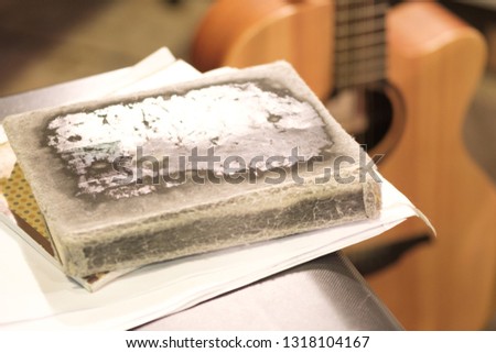 thick old book with battered crusts in the foreground, blurred guitar background on stage