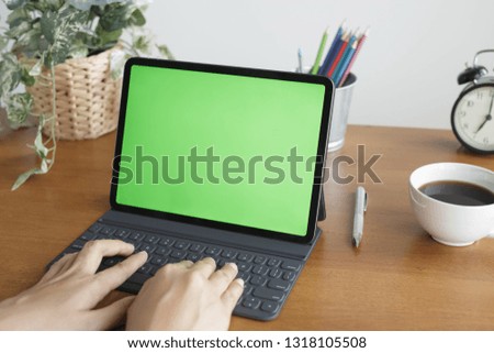 Asian woman hands are using tablet has a green screen on the desk