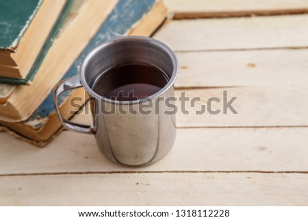 Vintage mug with drink and vintage books on wooden background. Top view