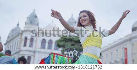 Happy Caucasian woman dancing in the carnival of Brazil with the typical scenario of Recife. Frevo dancing.