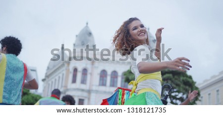 Happy Caucasian woman dancing in the carnival of Brazil with the typical scenario of Recife. Frevo dancing.