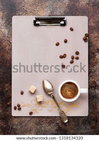 Vntage clipboard, cup coffee and coffee beans on dark background, top view