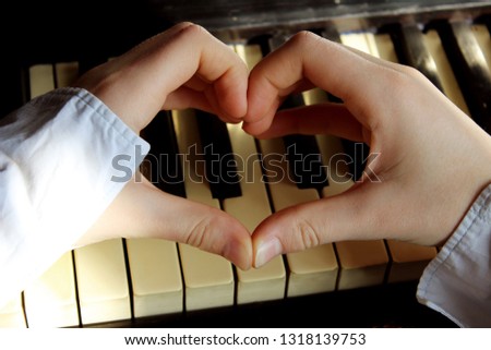 Heart Shape Over Piano Background.Shot Of An Unidentifiable Female Hands Making A Heart Shape Over A Piano. Love Of Music Concept.
