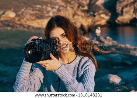 woman in a sweater in nature holding a camera with a large lens                               