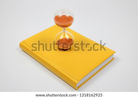 Book on the table. Book and hourglass. Yellow notepad and clock. On a white background.
