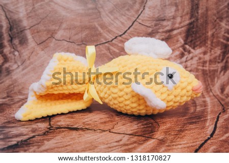 handmade crochet fish of yellow color on wooden background