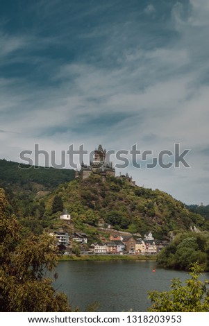 View of Reichsburg castle of Cochem with a amazing sky of background. It is can be found in the city of Cochem. The castle is set on a green hill overlooking the River Moselle.