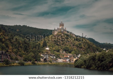 View of the Gothic Cochem Castle with a beautiful sky background, towering above the scenic town of Cochem on the Moselle River.