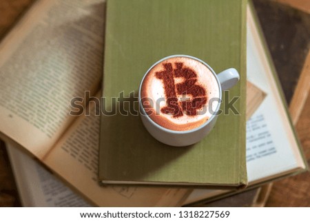 a cup of cappuccino coffee with a bitcoin symbol on a milk crema