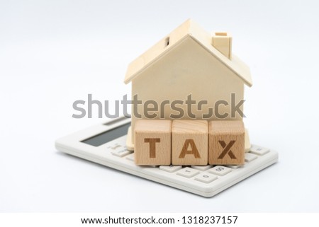 A model house model is placed on wood word TAX . as background property real estate concept with copy space for your text or  design.