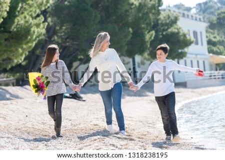 Mother together with her son and her daughter on the beach, recieving gifts from them, celebrating womans day