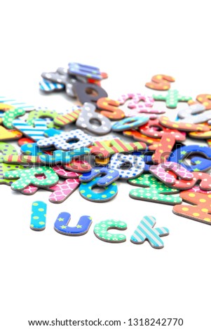 heap of funny colorful paper letters with stars, dots and stripes and the word luck isolated on white background with copy space
