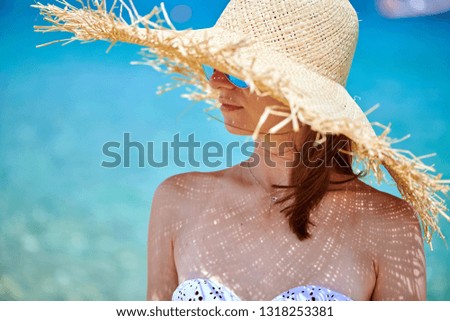 Woman in bikini wearing sunglasses and straw sun hat on beach. Summer vacation portrait. Sithonia, Greece