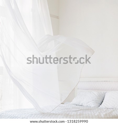 Closeup of white waving curtain on window in white bedroom Royalty-Free Stock Photo #1318259990