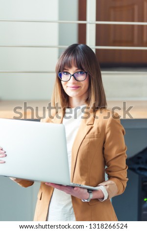 Beautiful young woman in eyeglasses worker holding laptop 