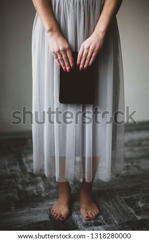 girl in a long skirt is barefoot on the floor, without shoes, holding a notebook in her hands Royalty-Free Stock Photo #1318280000