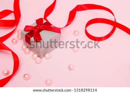 Gift on a pink background with beads and a red ribbon