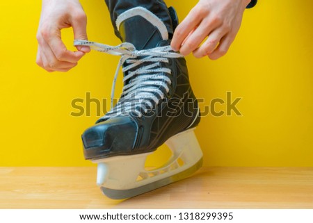 person tying shoelaces on a skates before skating in an ice rink