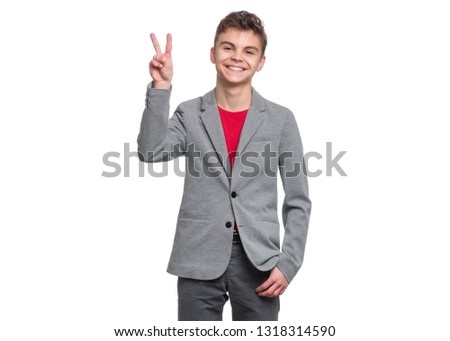 Handsome Teen Boy in suit making Victory Gesture. Portrait of caucasian Smiling Teenager isolated on white background. Happy child looking at camera.