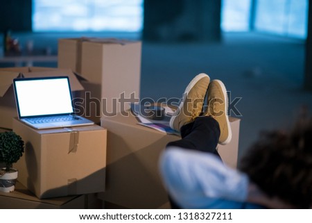young businessman on construction site taking a break while checking documents and business workflow with cardboard boxes around him in new startup office