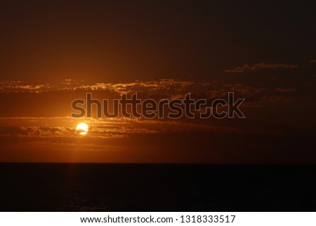 Slightly cloudy sunset at calm ocean