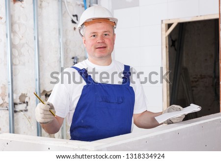 Portrait of satisfied construction worker standing at indoors building site
