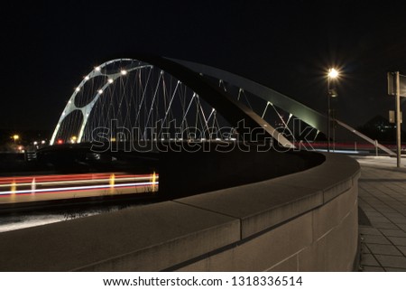 Osthafen bridge in Frankfurt, Germany with lights of a boat passing by at night