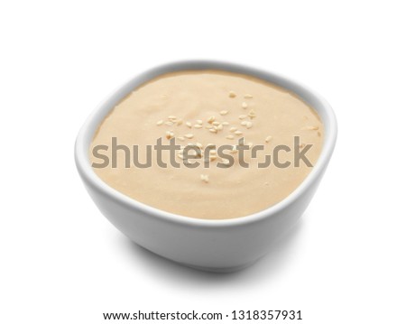Bowl of tasty tahini on white background Royalty-Free Stock Photo #1318357931