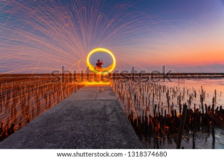 A ring of fire spinning steel wool on the rock and beach, Showers of hot glowing sparks from spinning steel wool on the rock and beach