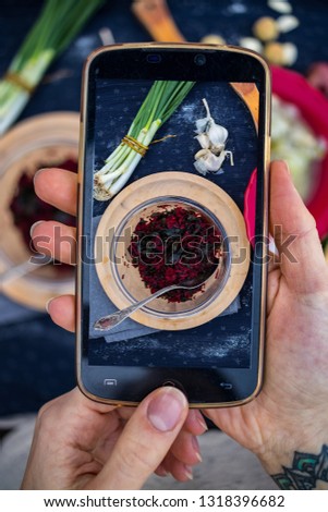 Smartphone food photography. Woman hands take phone food photo. Veggie dinner with salad, table, black dark background. Vegetarian healthy lunch. Blogging or social networks style. Top, above view.