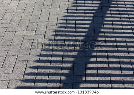 Cobbles and the shadow of a fence