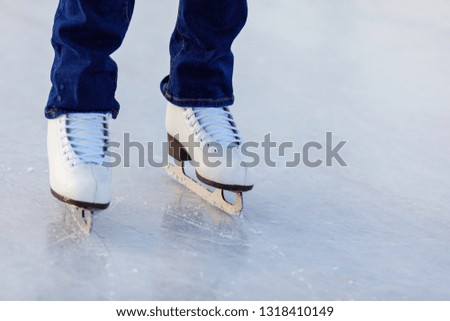Legs of skater girl in skates on the rink in winter