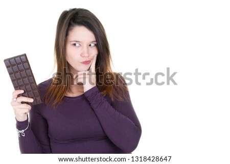 beautiful woman hesitates to eat chocolate with the finger on the cheek