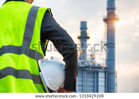 engineering man with white safety helmet standing in front of oil refinery building structure in heavy petrochemical industry 