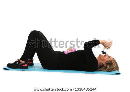 Fit middle aged woman doing exercises on a yoga mat with dumbbells against a white background