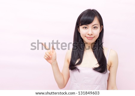 young woman pointing copy space against pink background