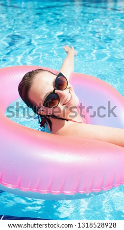 A young girl is relaxing in a pool with a swimming circle. The girl laughs. The rest in the hotel is all inclusive. Summer rest