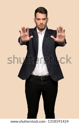 Handsome business man making stop gesture and disappointed over ocher background