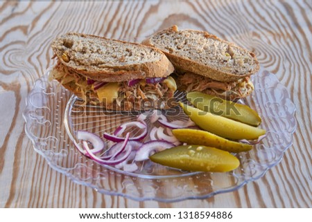  Close up picture of whole grain sandwich with pulled pork and sour cabbage and pickles served like light meal fast food street food served on glass plate on wooden table                              