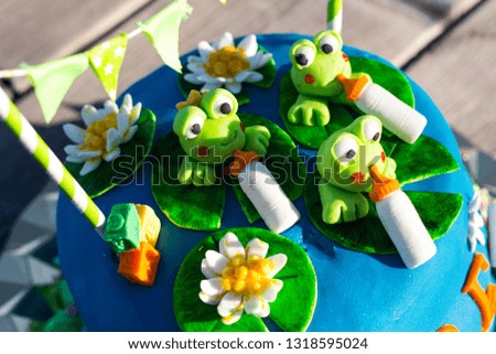 blue birthday cake with green frogs figures