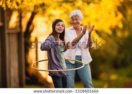 Senior woman watches her granddaughter hula hooping.
