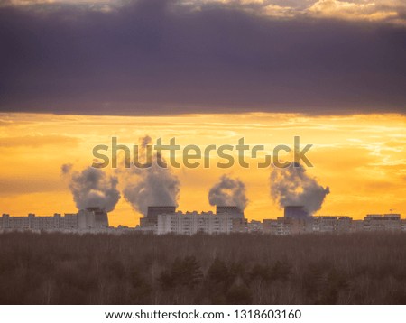 Four cooling towers of the heat power station over dark forest on sunset. Smoke or steam clouds from chimneys. Outskirts of the Moscow city, Russia. 