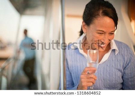 Middle-aged woman smiles while holding a champagne flute.