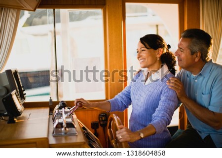 Woman driving a boat as her husband stands behind her