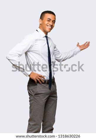 Young afro american businessman pointing back and presenting a product on isolated background