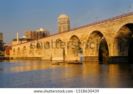 The Stone Arch Bridge reflected in the golden glow of sunrise on the Mississippi river at Minneapolis