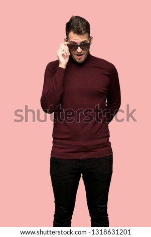 Man with turtleneck sweater with glasses and surprised over pink background